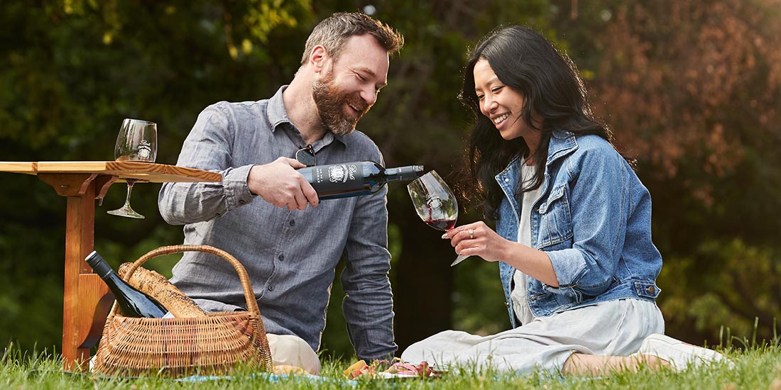 Man and a woman drinking wine at a pinic. 